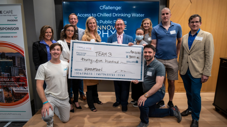 Group standing together to hold large check 